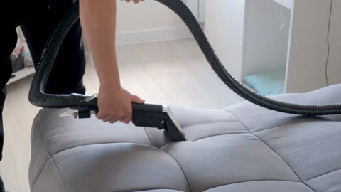 Cleaner hands using vacuum cleaner on sofa to remove dust, dirt and stains. Stock Footage 311799552