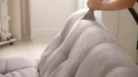 Cleaner tackles sofa with vacuum cleaner, removing accumulated dirt stains. Stock Footage 311801065