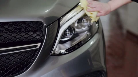The cleaner wipes the front headlight of a prestigious car with a rag. Stock Footage 155846199