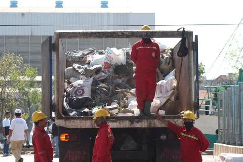 The cleaners are collecting garbage into the garbage truck Photos