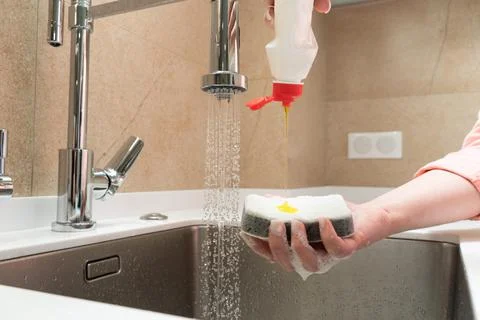Cleaning agent flows onto the sponge in the kitchen Stock Photos