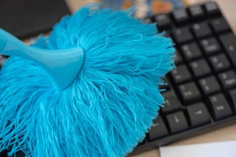 Cleaning and caring computer keyboard with a blue brush from dust. Stock Photos