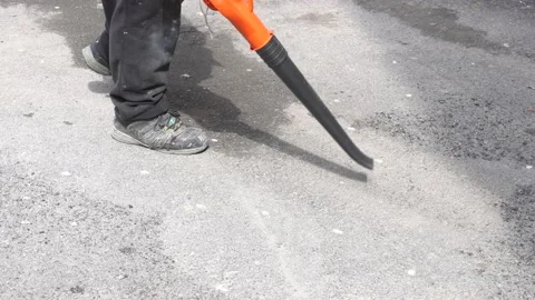 Cleaning an asphalt surface with a wind blower 스톡 동영상 134514591