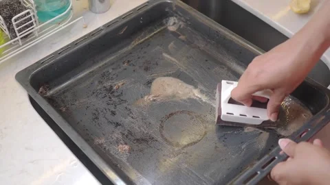 Cleaning a baking tray in the kitchen with a scrubbing tool Stock Footage 345473023