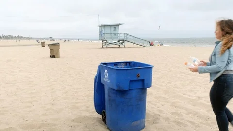 Cleaning the beach, dumping trash in a recycle bin, wide shot Video stock 107890145