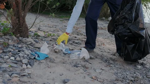 Cleaning Up Beach or Forest. Mixed Race Volunteer Raises and Throws a plastic Stock Footage 148186476