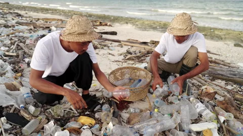 Cleaning up beach from plastic bottles on sand beach. Two asian men recycling Stock Footage 227436151