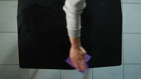 Cleaning black table with purple sponge at home, close up of hand wiping surface Stock Footage 315111412