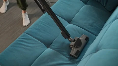 Cleaning a blue couch with a vacuum cleaner in detailed close-up views. A woman Video stock 307552108