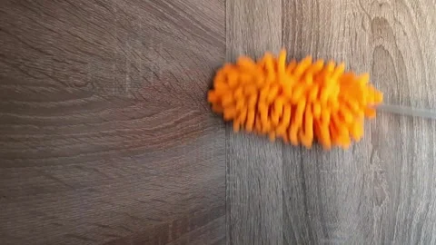 Cleaning the bookshelf from dust using an orange microfiber duster. Stock Footage 289452533
