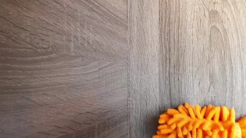 Cleaning the bookshelf from dust using an orange microfiber duster. Stock Footage 289452538