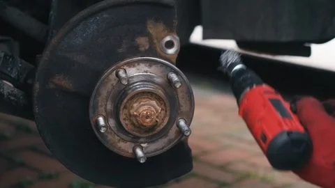 Cleaning brake caliper mounting surfaces on wheel hub with rotary wire brush Video stock 344537971
