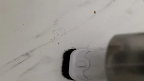 Cleaning bread crumbs from the surface of a white table with a cordless vacuum Stock-Footage 202010089