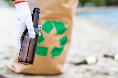 Cleaning city beach from trash concept. Female volunteer is picking up glass  Foto stock