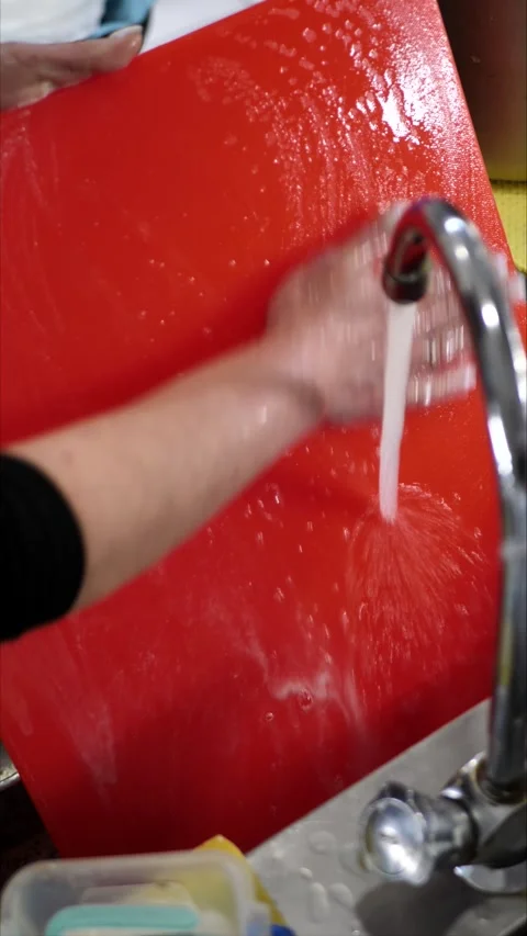 Cleaning a cutting board in the sink with soap and water while working in the Stock Footage 306009556
