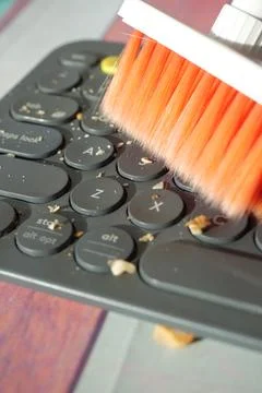 Cleaning debris from a computer keyboard with a brush Stock Photos