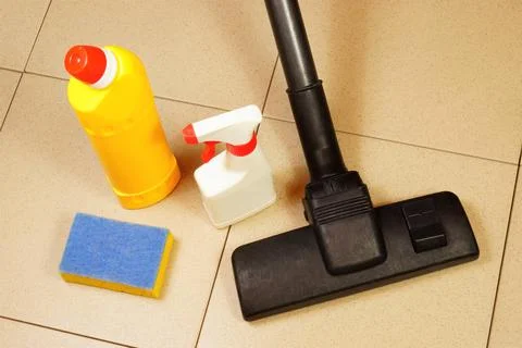 Cleaning of debris from the tile floor surface with a brush vacuum cleaner. Stock Photos