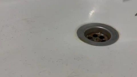 Cleaning a dirty sink drain to remove debris and improve hygiene Stock Footage 311570362