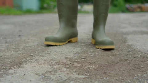 Cleaning efficiently and thoroughly with Green Rubber Boots and a Broom on the Stock Footage 309333997