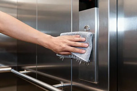 Cleaning elevator buttons with a cloth for hygiene and safety Stock Photos