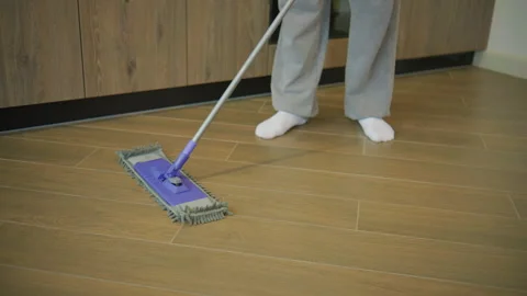 Cleaning the floor in a home setting with a mop during the afternoon hours while Stock Footage 345288664