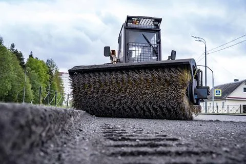 Cleaning of garbage from the road. a rotating mechanical machine brush 库存照片