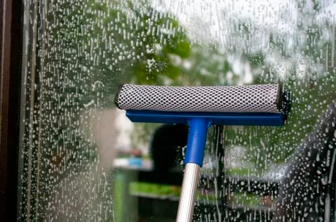 Cleaning glass of window using a squilgee. Stock Photos
