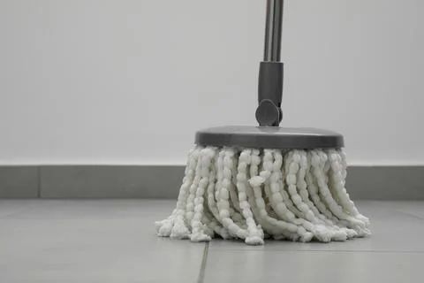 Cleaning grey tiled floor with string mop, closeup. Space for text Stock Photos