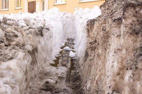 Cleaning the gutter from snow in the spring to drain meltwater from the build Stock Photos