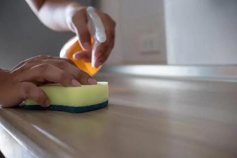 Cleaning her house using a spray and a duster cleans Stock Photos