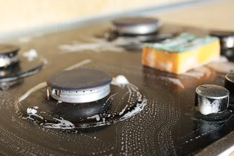 Cleaning the hob in the kitchen with detergent to remove grease Foto stock