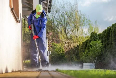 Cleaning House Backyard Brick Paths Using Pressure Washer.  库存照片