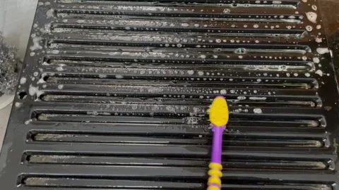 Cleaning kitchen chimney mesh on Black Grill Surface with Scrub Brush Stock Footage 337722363