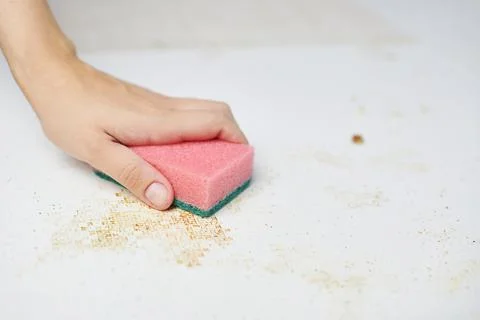 Cleaning kitchen table. Pink sponge in woman hand removes dirt, bread crumbs  Stock Photos