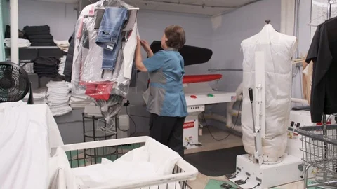 A cleaning lady does laundry in a hotel's industrial room Stock Footage 122857337