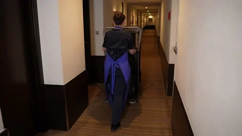 Cleaning lady driving trolley down hotel corridor Stock-Footage 148153487