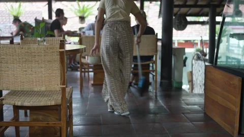 A cleaning lady in a summer cafe, cleans the floor, sweeps the garbage Stock Footage 244598696