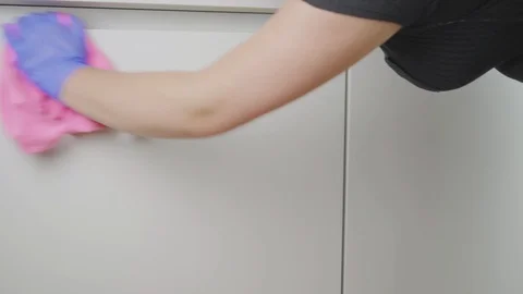 Cleaning lady using a cloth to clean white kitchen cabinets in a luxury home Stock Footage 91030296