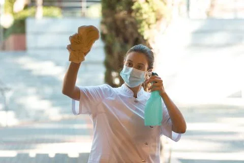 Cleaning lady using a face mask while cleaning the window. Stock Photos