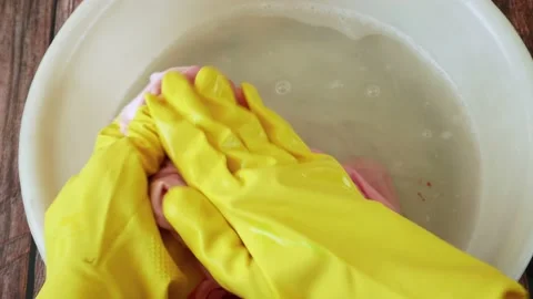 Cleaning laundry manually. Women's hands in gloves washing dirty stained on c Stock Footage 186700705