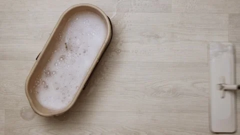 Cleaning a light wood floor with a mop and soapy water bucket Stock Footage 339070221