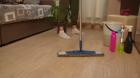 Cleaning in a living space using a mop. A woman is mopping the floor with a mop Stock-Footage 311051396
