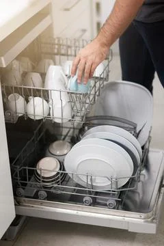 Cleaning, loading dishwasher and hands with dishes in the kitchen for housework Stock Photos