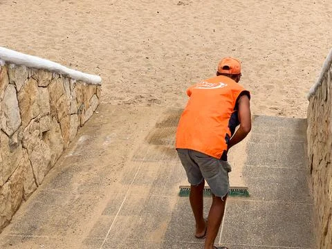 Cleaning man sweeping the pathway to the beach Stock Photos