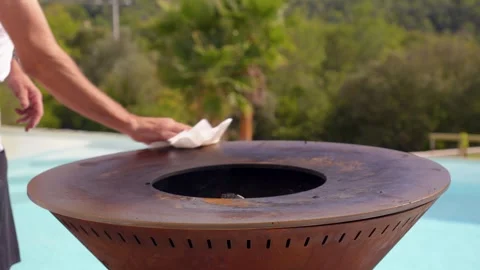 Cleaning metal fire pit cooking surface with cloth Stock Footage 326052284