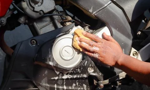 Cleaning a motorcycle engine and body with a soapy sponge Stock Photos