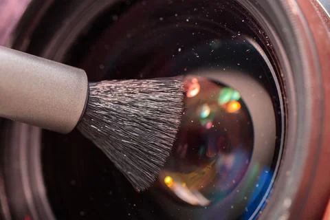 Cleaning the objective lens from dust with a special brush. close-up. Stock Photos