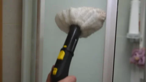 Cleaning person using steam cleaner to remove dirt and grime from glass door of Stock Footage 296271499