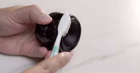 Cleaning a piece of camera lens using a soft-bristled toothbrush to take Stock Footage 277196495