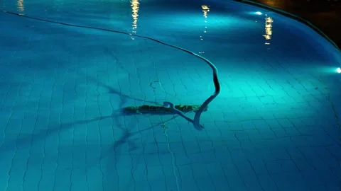 Cleaning the pool bottom with a water vacuum cleaner in the evening. Stock Footage 326868858